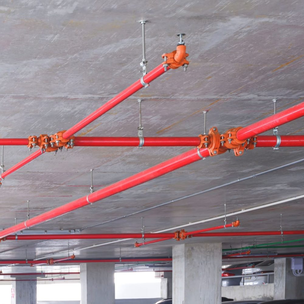 Red fire protection water pipeline system on ceiling inside of parking garage building